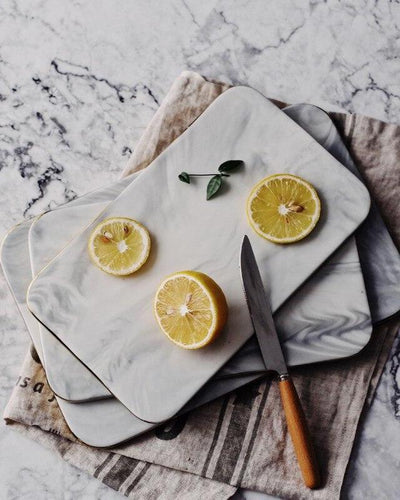 Marble board in white with golden finish next to a knife with lemons