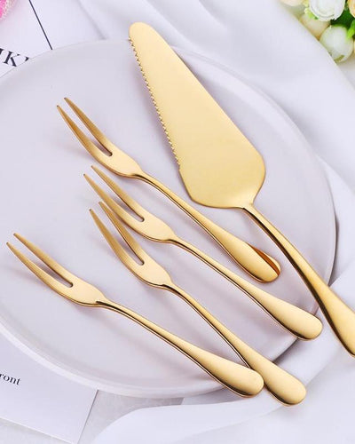 Cake serving set on a white plate, one spatula and four forks in golden color